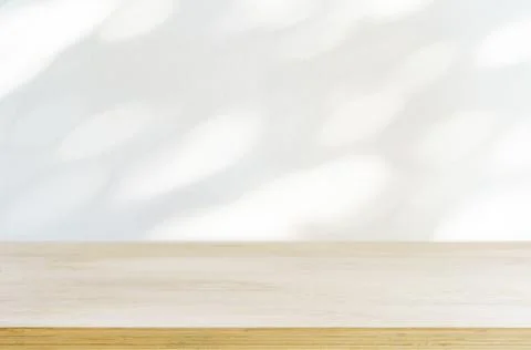 Table shadow background. Wooden table and white empty wall with plant shadows. Stock Photos
