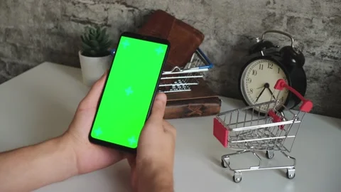 Table with shopping baskets close-up mobile phone in hands with green screen Stock Footage 146595272