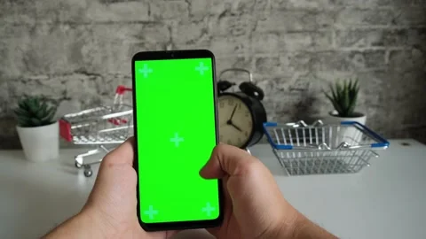 Table with shopping baskets close-up mobile phone in hands with green screen Stock Footage 146596515