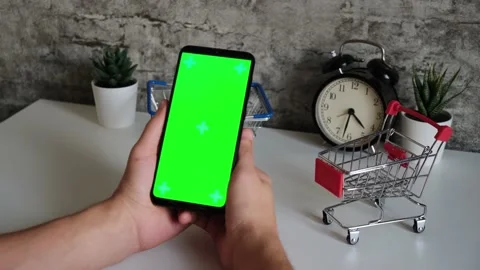 Table with shopping baskets close-up mobile phone in hands with green screen Stock Footage 147245682
