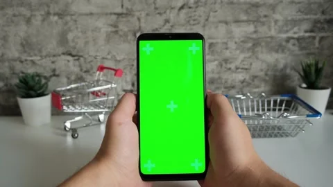 Table with shopping baskets close-up mobile phone in hands with green screen Stock Footage 147385898