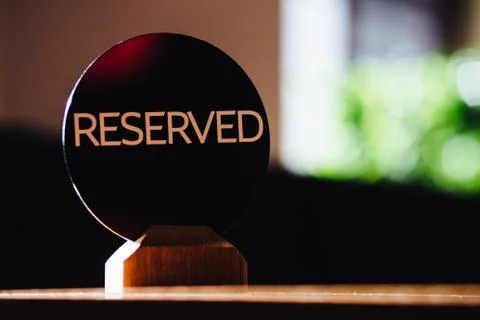Table sign denoted reserved table in restaurant stands against blurred cafe b Stock Photos