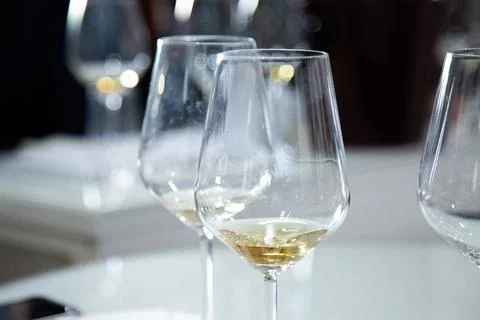 On the table sit three wine glasses filled with white wine Stock Photos