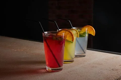 On the table, soft drinks, various cocktails, a glass with a straw and a slice Stock Photos