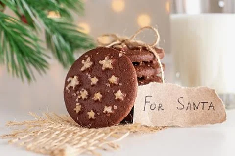 On the table is a stack of round chocolate Christmas cookies and glass of milk Stock Photos