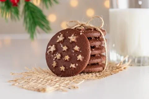On the table is a stack of round chocolate Christmas cookies and glass of milk Stock-Fotos