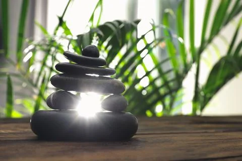 Table with stack of stones and blurred green leaves on background, space for  스톡 사진