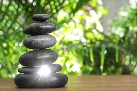 Table with stack of stones and blurred green leaves on background, space for  스톡 사진