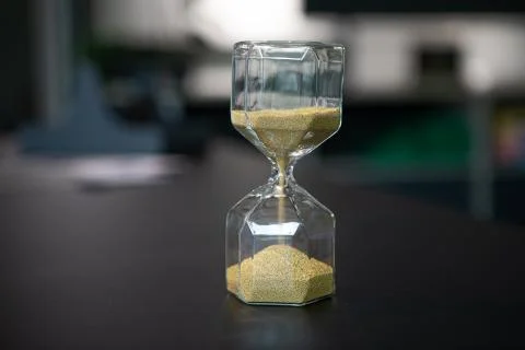 On a table stand an egg timer made of glass, which is filled with small balls Stock-Fotos
