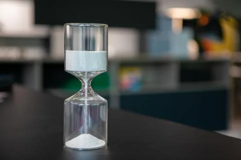 On a table stand an egg timer made of glass, which is filled with small balls Foto stock