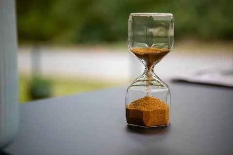 On table stand an egg timer made of glass, which is filled with small ball... Stock Photos