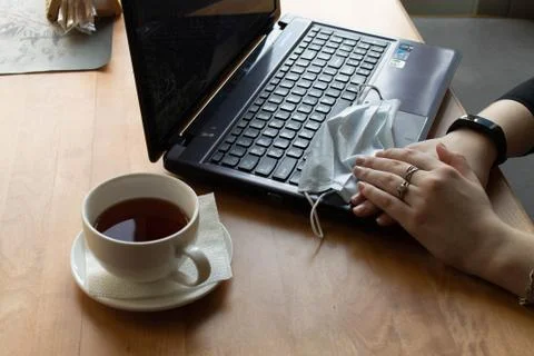On the table stands to the laptop, next to a mug of tea. hands lie on a medical Stock Photos