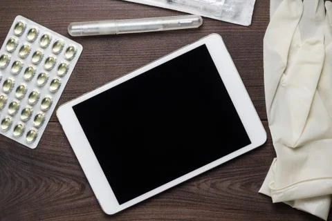 Table with tablet computer pills and gloves on it Stock Photos