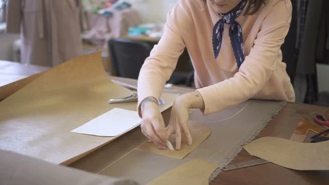 On table tailor circled with a chalk a pattern on material for sewing. Stock Footage 87323787