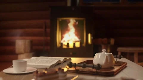 Table with teapot and cups. Open book. Cozy interior with chimney. Stock Footage 252149999