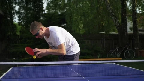 Table tennis player preparing for serve. Man player in garden setting with ball Stock Footage 130666238