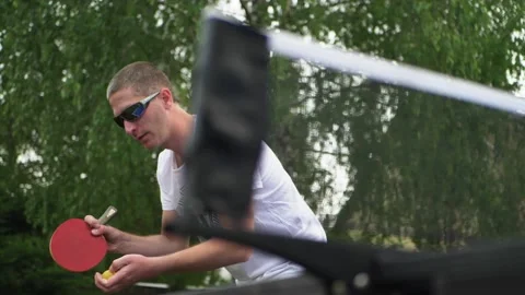 Table tennis player preparing for serve. Man player in outdoor garden setting Stock Footage 130666282