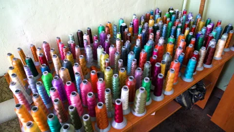 On the table there are a large number of colorful spools of thread. Coils for Stock Footage 195023076