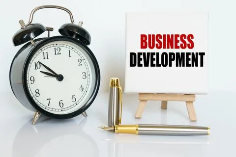 On the table there is a clock, a pen and a stand with a card on which the tex Stock Photos