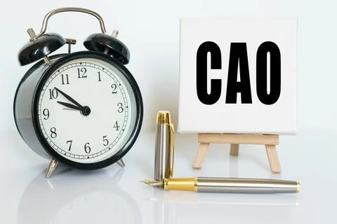 On the table there is a clock, a pen and a stand with a card on which the tex Stock Photos