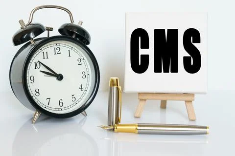On the table there is a clock, a pen and a stand with a card on which the tex Stock Photos