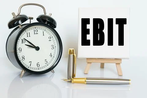 On the table there is a clock, a pen and a stand with a card on which the tex Stock Photos