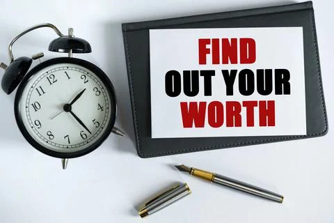 On the table there is a clock, a pen, a notebook and a card on which the text Foto stock