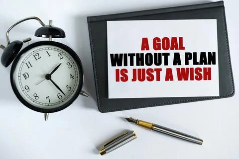 On the table there is a clock, a pen, a notebook and a card on which the text Foto stock