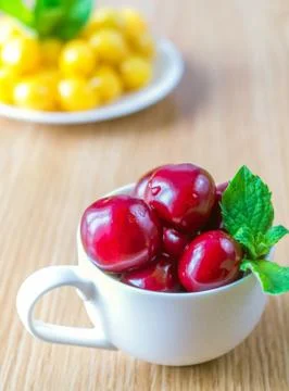 On a table there is a cup with a sweet cherry. Stock Photos
