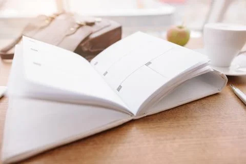 On the table there is a diary, a bag, a pen and a cup of coffee Stock Photos