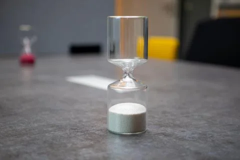 On  table there is a glass egg timer filled with small balls Stock-Fotos