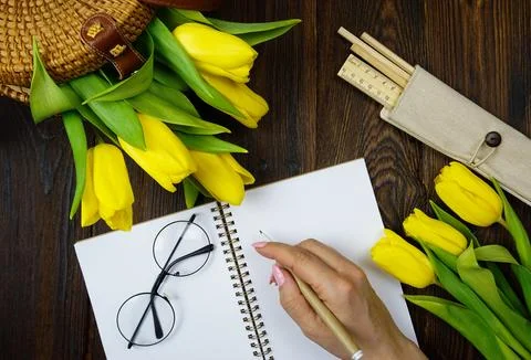 On the table there is a notebook for notes and beautiful yellow tulips Stock Photos