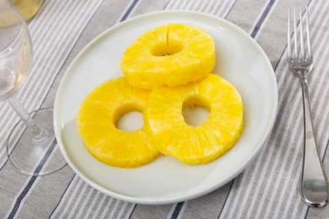 On table there is plate with summer dessert - round pieces of pineapple pulp. Stock Photos