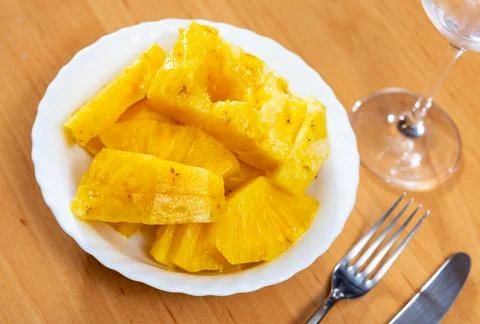 On table there is plate with summer dessert - pieces of pineapple pulp. Stock Photos