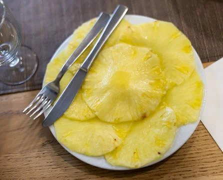 On table there is plate with summer dessert - round pieces of pineapple pulp. Stock Photos