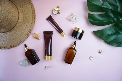 On the table there is a straw hat, a green leaf of a tropical plant, cosmetics Stock Photos