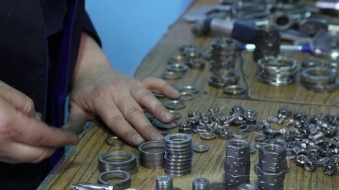 A table with tools. The worker unfolds the screws and nuts on the table. Stock Footage 82800505