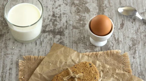 Table top of cookies, soft boiled egg, and a glass of milk on a rustic wooden Stock Footage 67850064