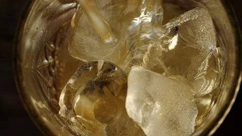 Table top pouring the alcohol drink to the glass with ice cubes in slow motion Video stock 163540924
