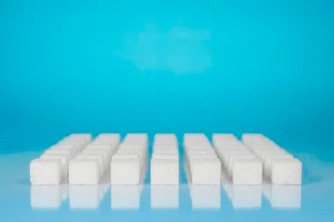 Table top shot Group of Sugar cubes vary position on light blue background Stock Photos