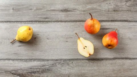 Table top view, ripe pears, one cut in half, on gray wood desk. Stock Photos