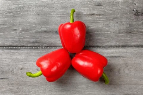 Table top view, three bright red bell peppers arranged into triangle with gra Foto stock