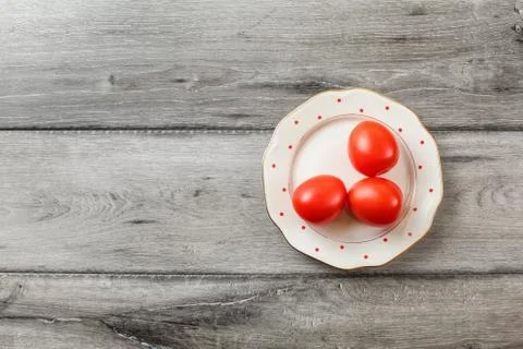 Table top view - three fresh tomatoes on white plate with small red dots and  Stock Photos