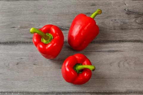 Table top view - three red bell peppers on gray wood desk. Stock Photos