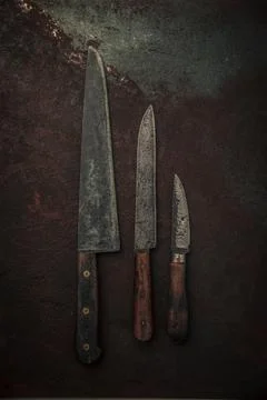 Table top view of three rustic knives on old rusty metallic background Stock Photos