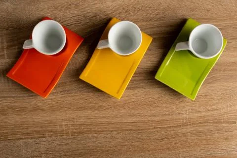 Table top view of three white coffee cups placed on coloured dishware. Foto stock
