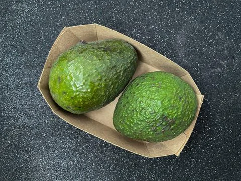 Table top view - two whole avocado pears in the paper basket Foto stock
