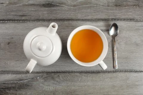 Table top view on white ceramic teapot,  cup of hot black tea, and silver spo Stock Photos
