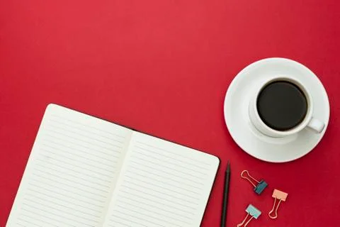 Table top, working desk with open notebook and coffee cup on red background.  Stock Photos