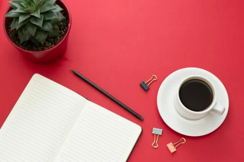 Table top, working desk with open notebook and coffee cup on red background.  Stock-Fotos